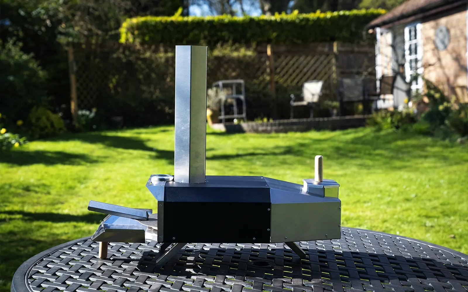 Pizza oven on a stainless steel table in a garden setting