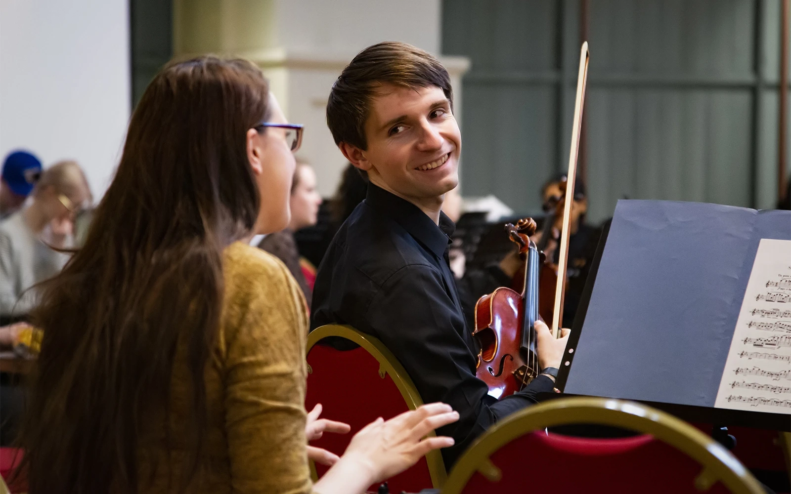 Two violinists chatting during a break in concert rehearsals