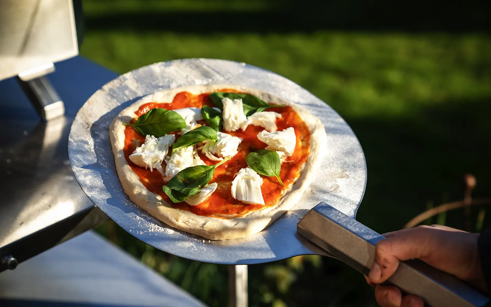 Close-up of an uncooked pizza on a pizza peel ready to put into the pizza oven