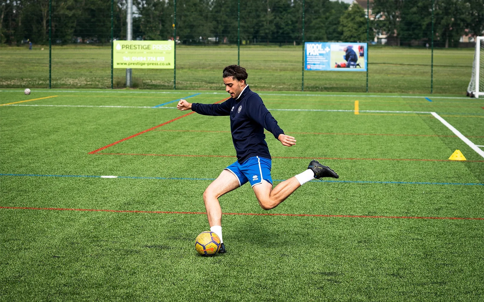 An action shot of a teenage boy during a football training session at a football pitch