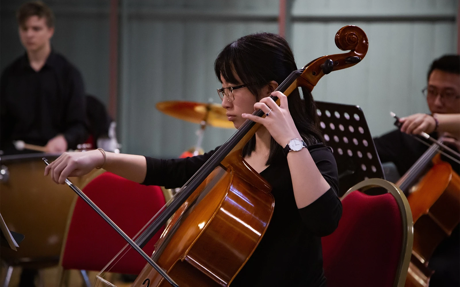 A young woman playing the cello during an orchestral concert