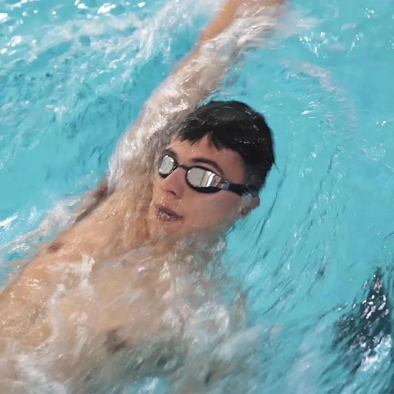 A man swimming backstroke and wearing goggles