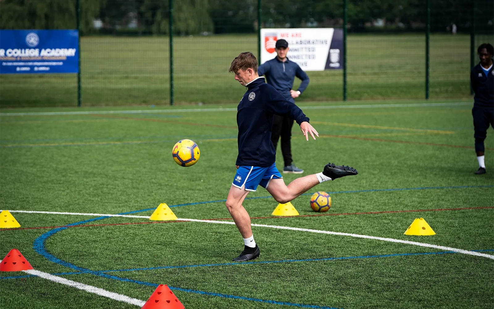 An action shot of a teenage boy during a football training session at a football pitch