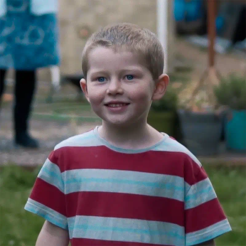 A still from the uPhotogifts promotional video showing a close up of a young boy wearing a red-striped t-shirt in the garden, smiling
