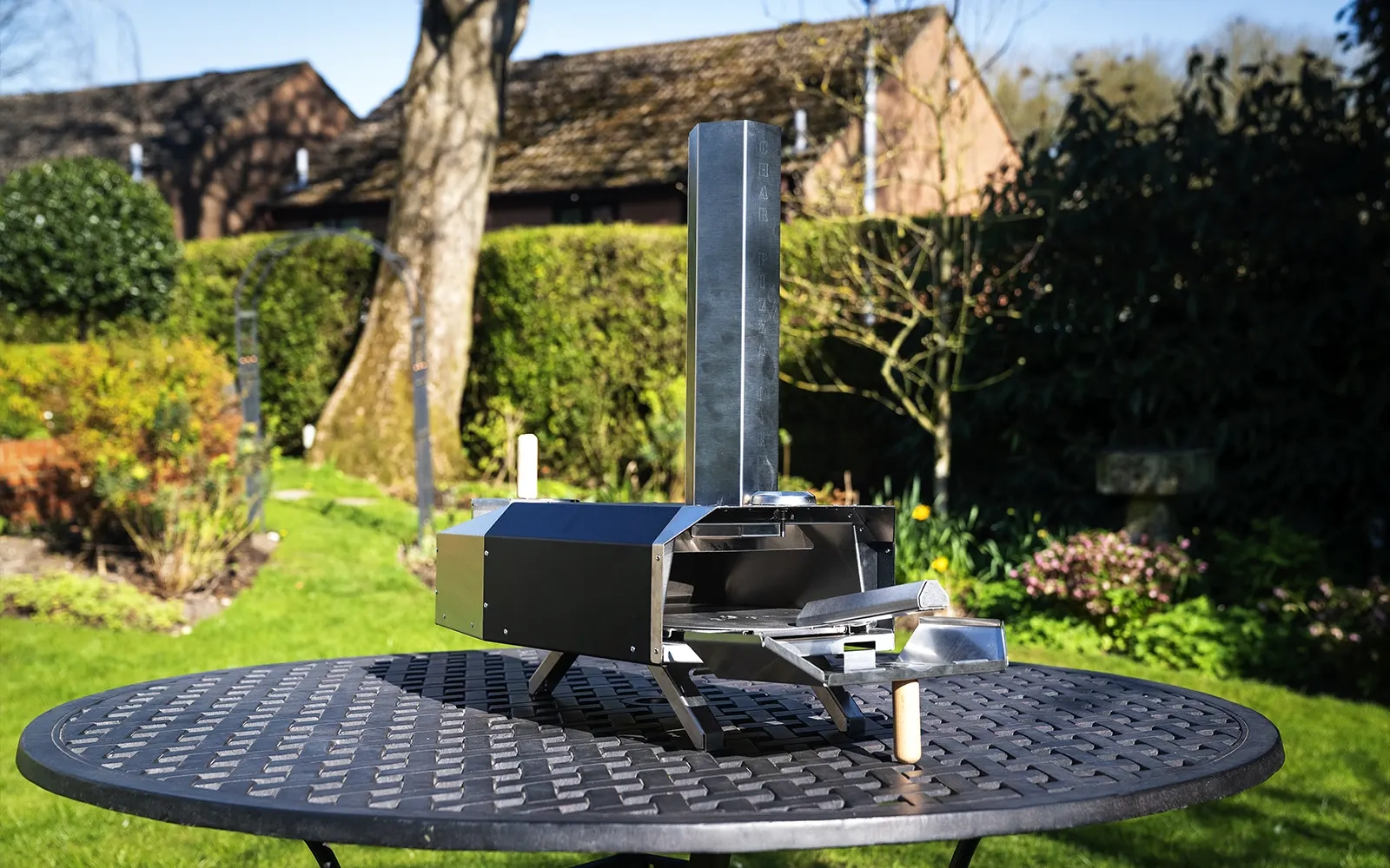 Pizza oven on a stainless steel table in a garden setting