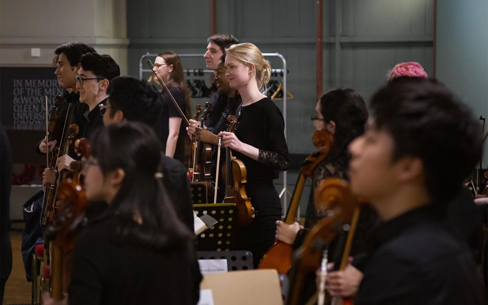 The strings section standing up to receive applause at the end of an orchestral concert