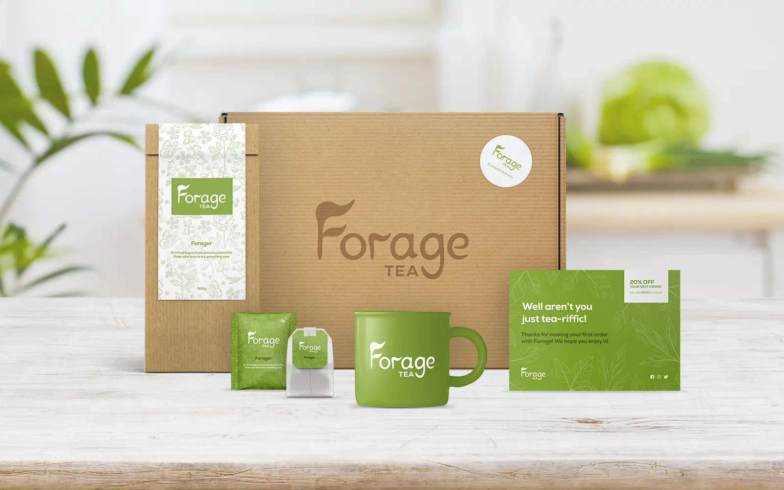 Packaging mockups with the Forage Tea branding including the outer box, inner packet, tea bag sachet and tea bag as well as a branded mug and discount card displayed in a well lit, white, modern kitchen